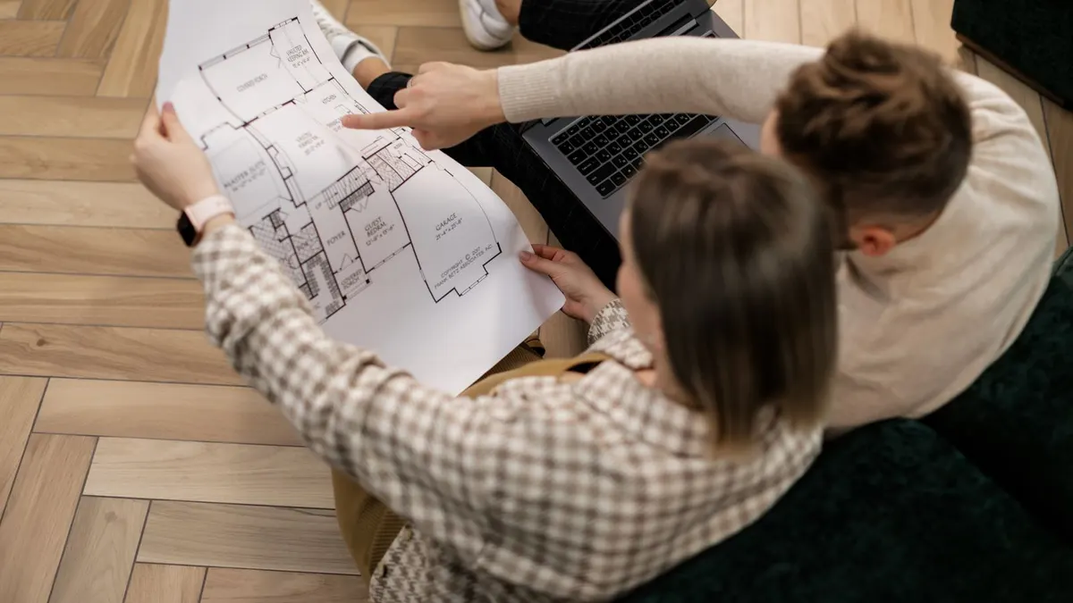 Plan architectural de logement neuf avec cotes, pièces colorées et annotations, posé sur une table